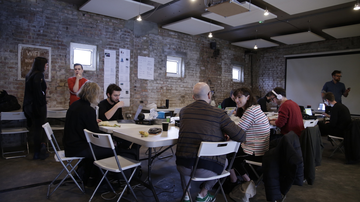 People sat around a table working on laptops, playing with smart speakers and generally looking busy and creative (Photo by Ric Leeson, © BBC 2018)